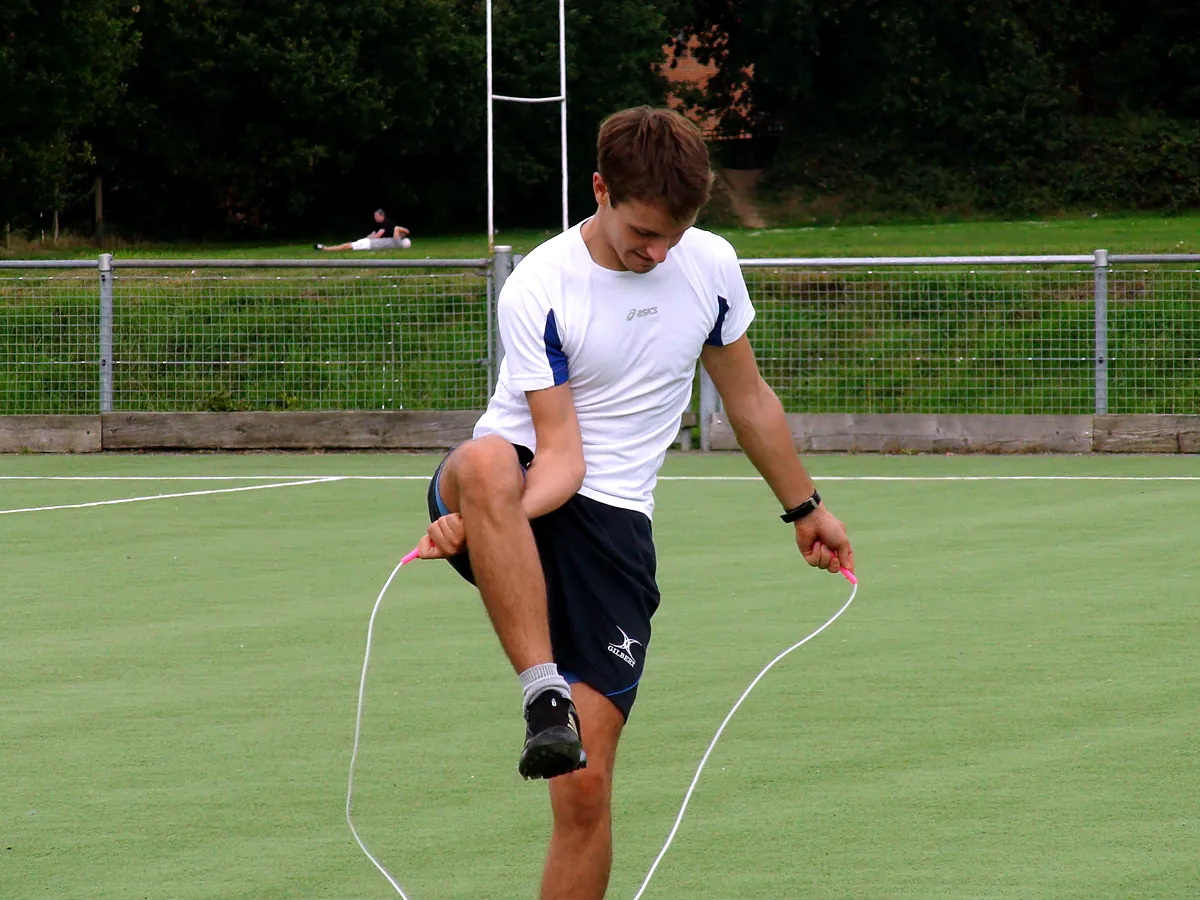 An adult skips with a high knee lift on a sports pitch